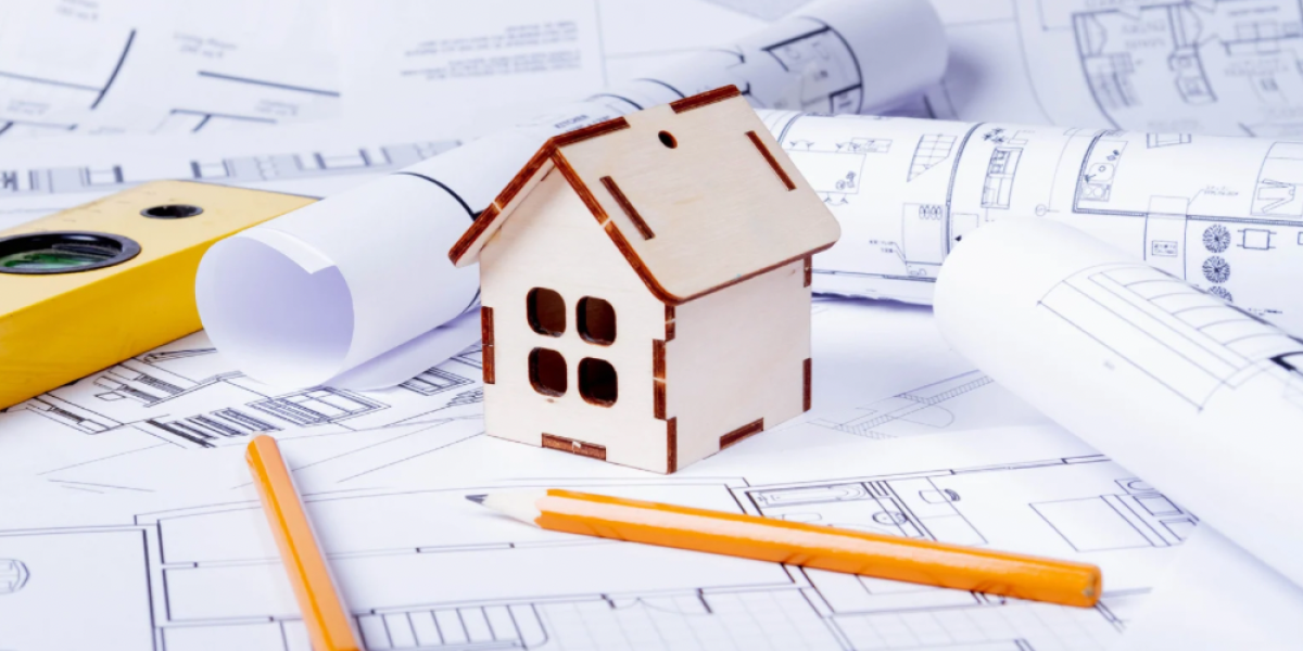A home model on building plans with pencil and level.